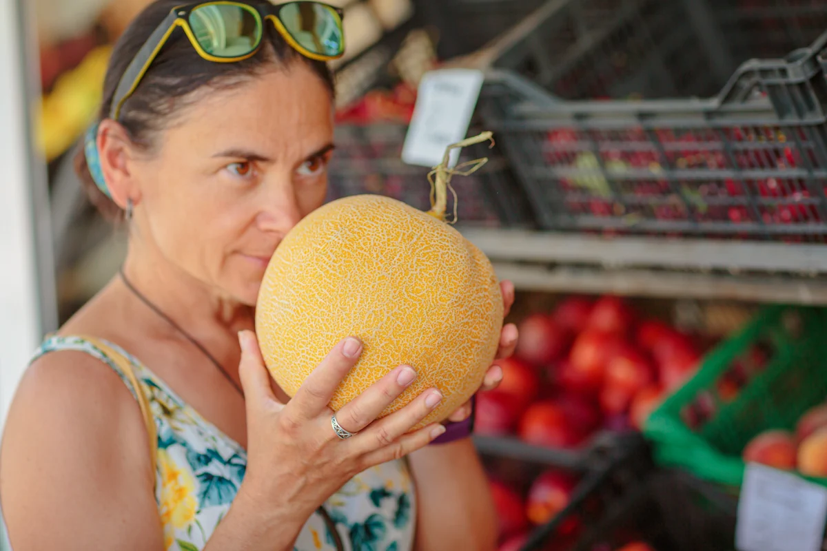 Une personne qui sent un melon jaune